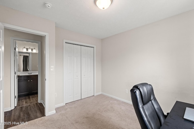unfurnished office with dark colored carpet, baseboards, and a sink