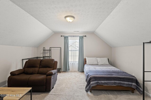 bedroom with vaulted ceiling, light carpet, a textured ceiling, and visible vents