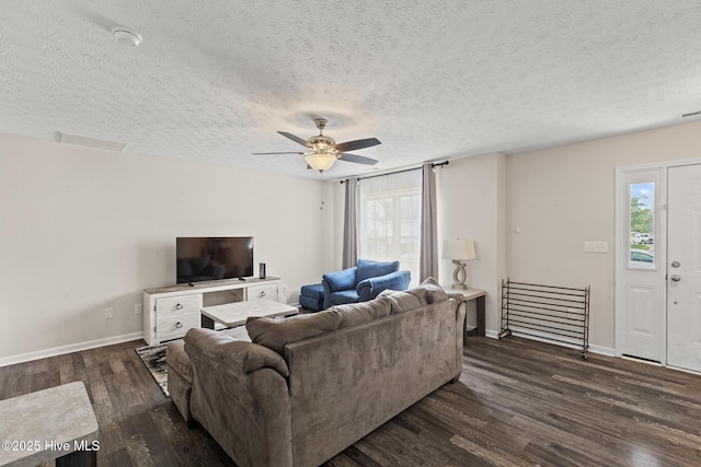 living area with ceiling fan, baseboards, dark wood-style flooring, and a textured ceiling