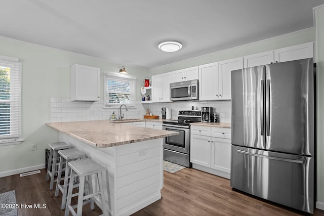 kitchen with stainless steel appliances, visible vents, a sink, a wealth of natural light, and a peninsula