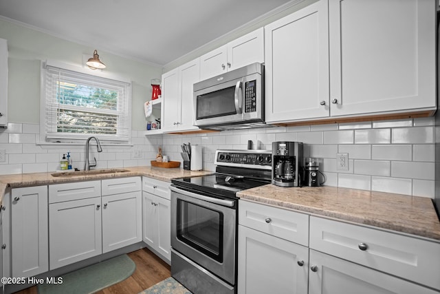 kitchen with a sink, white cabinetry, backsplash, and appliances with stainless steel finishes