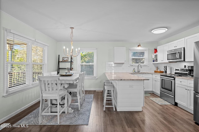 kitchen featuring tasteful backsplash, a breakfast bar area, stainless steel appliances, a sink, and a notable chandelier