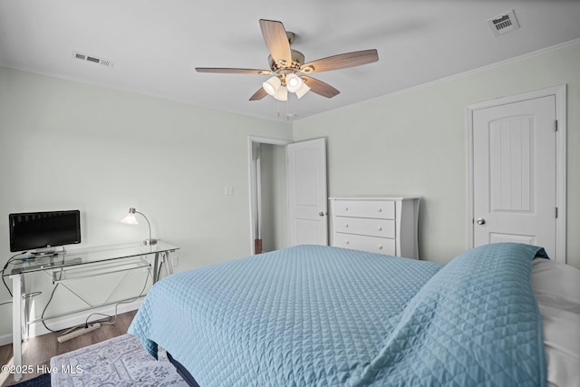 bedroom with visible vents, crown molding, ceiling fan, and wood finished floors