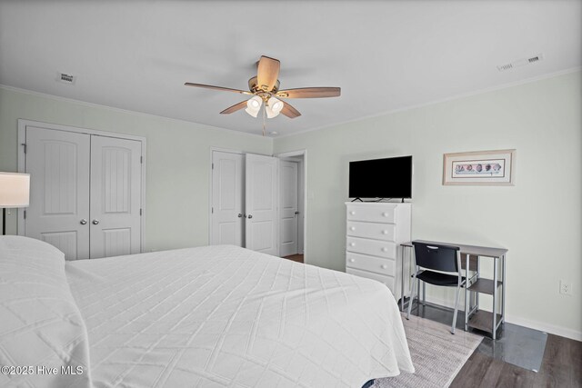 bedroom with baseboards, visible vents, crown molding, and wood finished floors