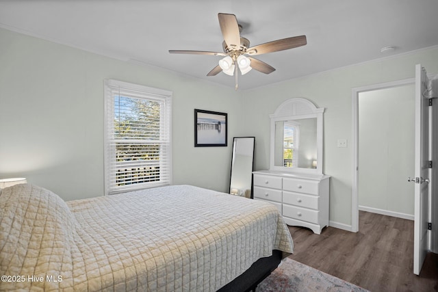 bedroom featuring baseboards, crown molding, wood finished floors, and ceiling fan