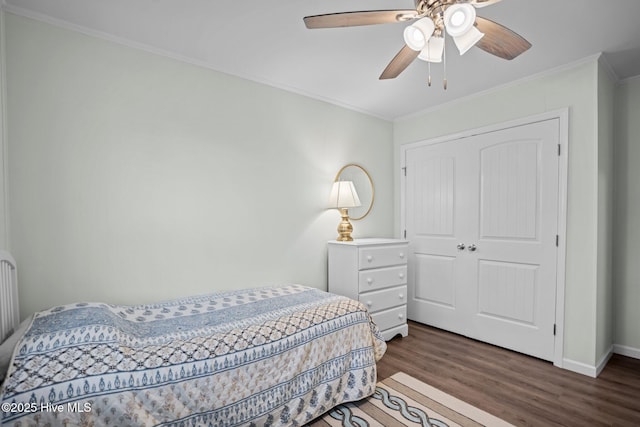 bedroom with a closet, wood finished floors, baseboards, ceiling fan, and ornamental molding