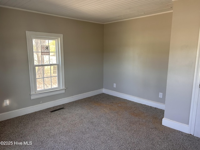 spare room featuring baseboards, visible vents, and dark colored carpet