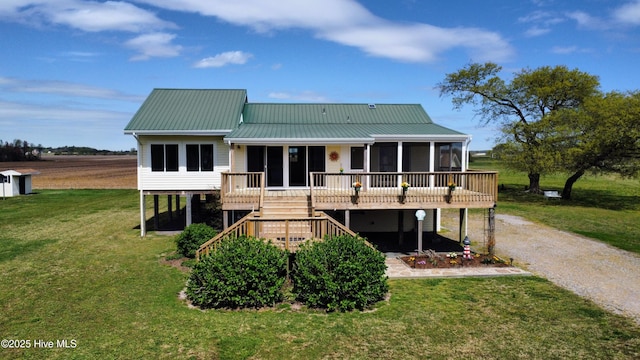 back of property with metal roof, a sunroom, stairway, driveway, and a yard