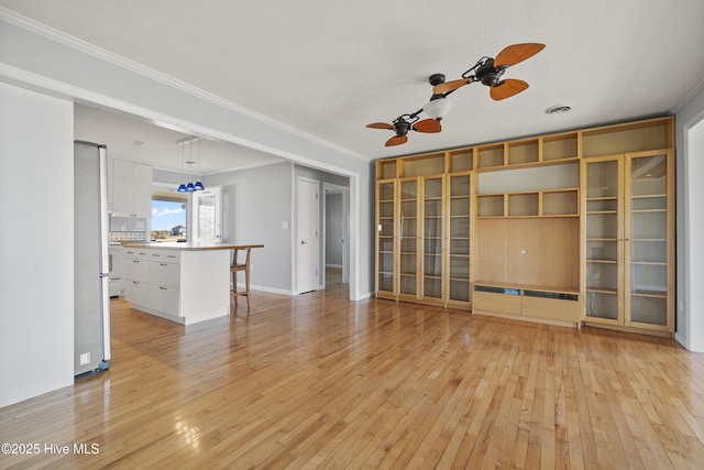 unfurnished living room featuring a ceiling fan, visible vents, ornamental molding, and light wood-type flooring