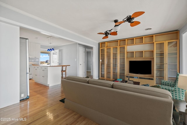 living area featuring visible vents, crown molding, a ceiling fan, and light wood finished floors