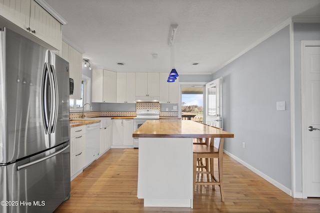 kitchen featuring white appliances, light wood-type flooring, crown molding, and a kitchen breakfast bar
