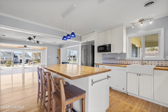 kitchen featuring visible vents, dishwasher, wood counters, black microwave, and freestanding refrigerator