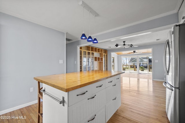 kitchen with a ceiling fan, light wood finished floors, freestanding refrigerator, butcher block counters, and ornamental molding