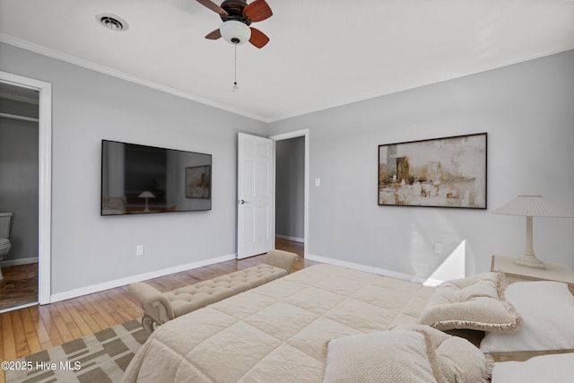 bedroom featuring baseboards, visible vents, crown molding, and wood finished floors