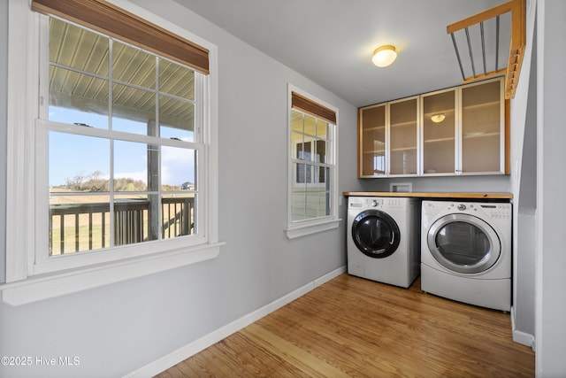 washroom with independent washer and dryer, light wood-style floors, and baseboards