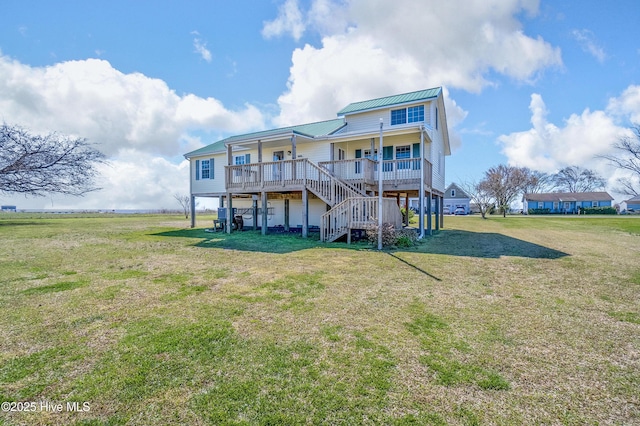 rear view of property featuring covered porch, stairway, a yard, and metal roof