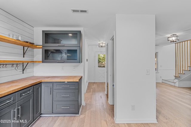 kitchen with light wood finished floors, wooden counters, open shelves, visible vents, and baseboards