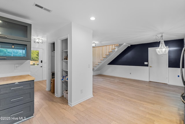 interior space featuring wood counters, light wood finished floors, an inviting chandelier, and visible vents
