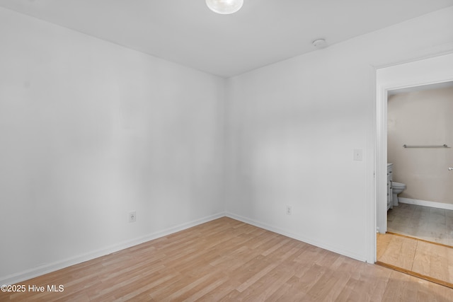 unfurnished bedroom with baseboards, ensuite bathroom, and light wood-type flooring