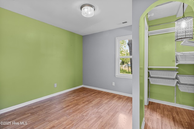 unfurnished bedroom featuring baseboards, a closet, visible vents, and wood finished floors