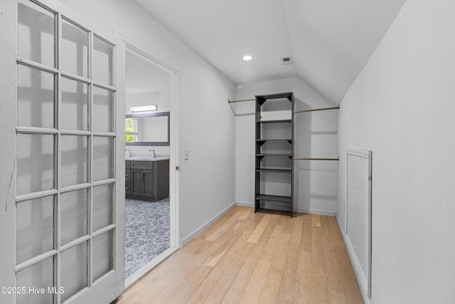 walk in closet featuring lofted ceiling, light wood-style floors, and a sink