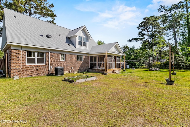 rear view of property featuring central AC unit, brick siding, a sunroom, and a lawn