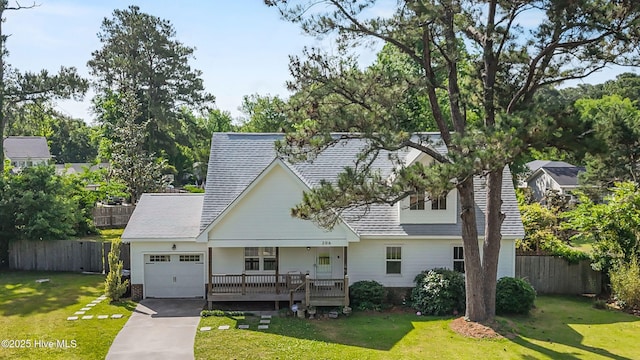 view of front of home with an attached garage, covered porch, fence, concrete driveway, and a front yard