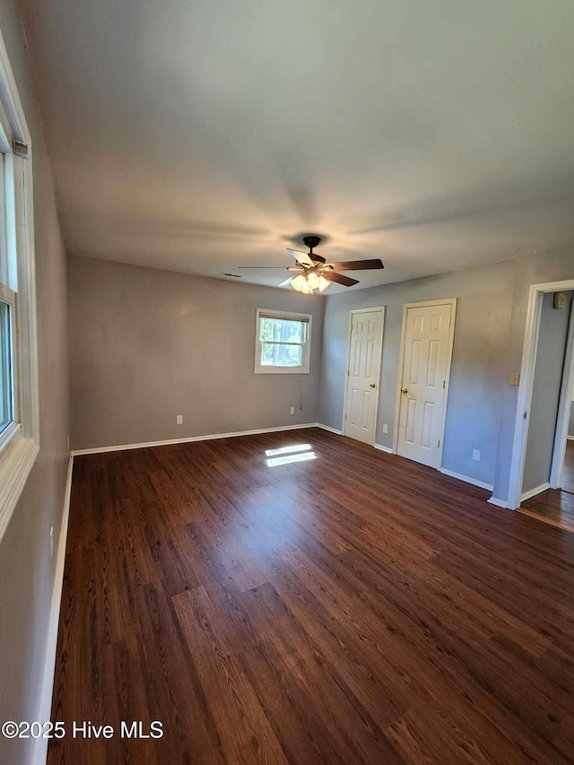 106 Hunters Trl E, Elizabeth City, NC 27909 - unfurnished bedroom featuring baseboards, two closets, ceiling fan, and dark wood-style flooring