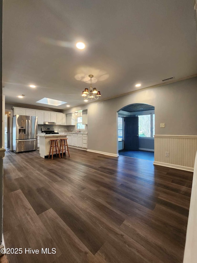 106 Hunters Trl E, Elizabeth City, NC 27909 - unfurnished living room with a chandelier, wainscoting, visible vents, arched walkways, and dark wood-style flooring