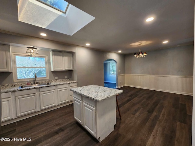 106 Hunters Trl E, Elizabeth City, NC 27909 - kitchen featuring a notable chandelier, a sink, dark wood-style floors, wainscoting, and arched walkways