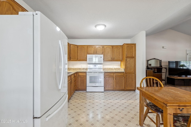 kitchen with brown cabinetry, light floors, light stone counters, and white appliances