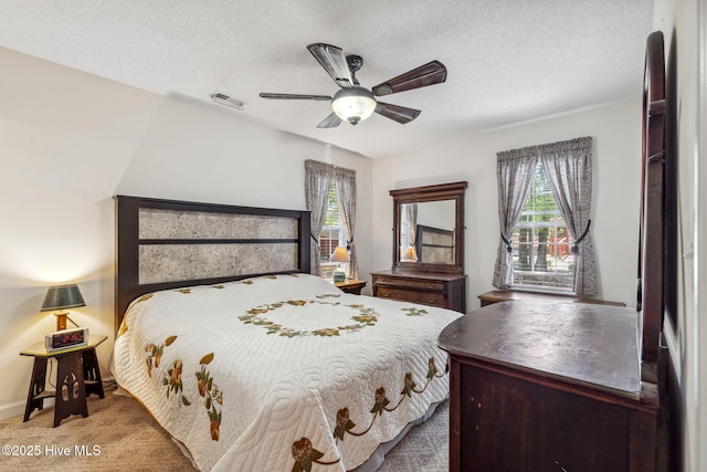 bedroom featuring visible vents, carpet flooring, a textured ceiling, and multiple windows