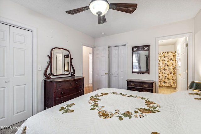 bedroom with two closets, ceiling fan, and ensuite bath