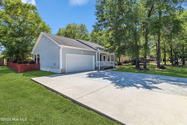 view of side of property with covered porch, an attached garage, concrete driveway, and a yard