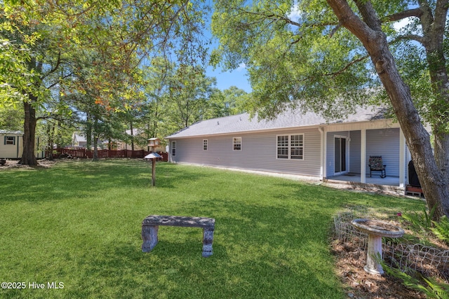 rear view of property featuring a lawn, fence, and a patio