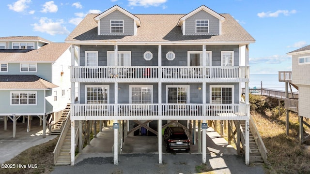 view of front of house with a shingled roof, stairway, and a carport