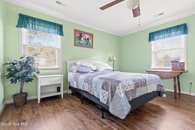 bedroom with visible vents, multiple windows, and wood finished floors