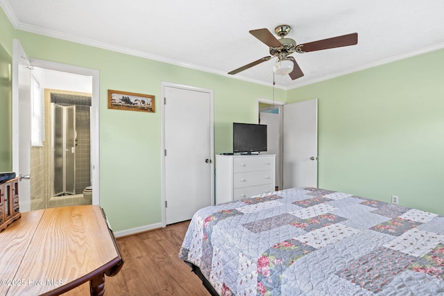 bedroom featuring crown molding, baseboards, ceiling fan, wood finished floors, and ensuite bath