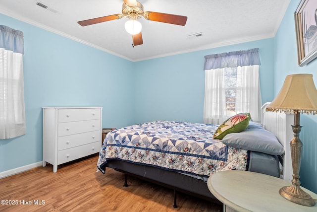 bedroom featuring visible vents, wood finished floors, and ornamental molding