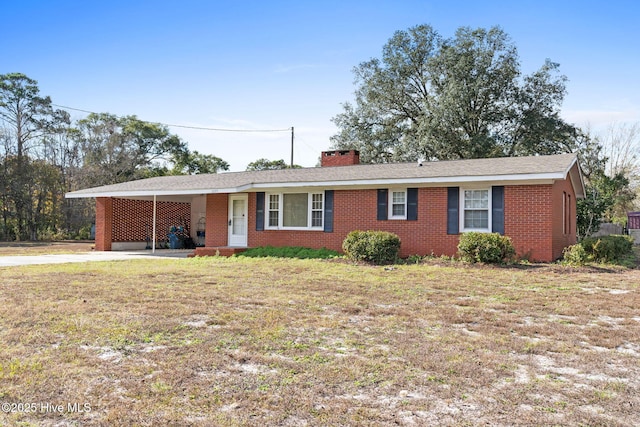 single story home with concrete driveway, an attached carport, a chimney, brick siding, and a front lawn