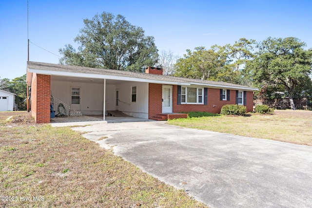 ranch-style home with a front lawn, an attached carport, a chimney, and concrete driveway