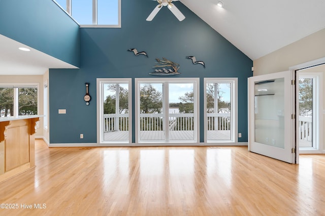 unfurnished living room with baseboards, a ceiling fan, light wood-type flooring, and plenty of natural light