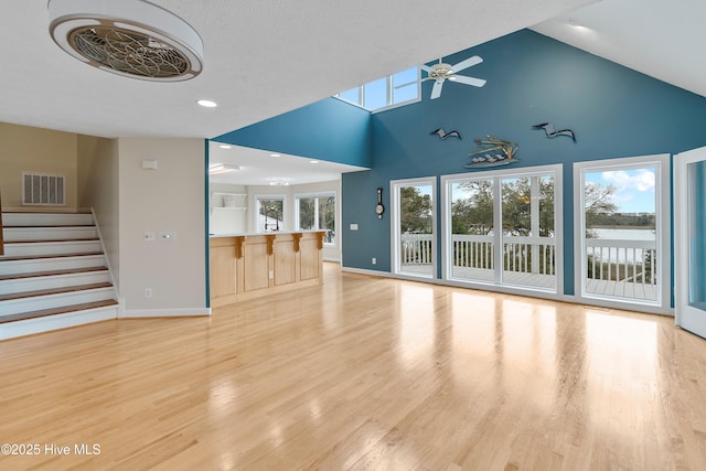 unfurnished living room featuring light wood finished floors, stairs, visible vents, and a ceiling fan
