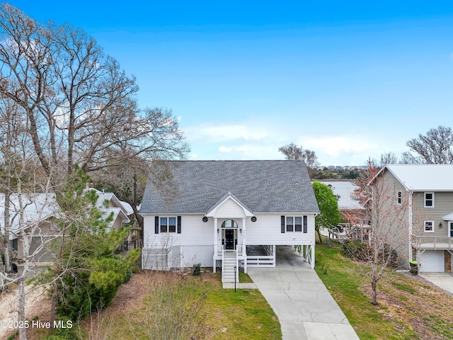 view of front of home featuring a front yard, concrete driveway, roof with shingles, and a carport