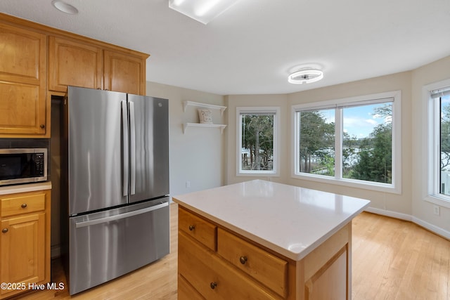 kitchen featuring stainless steel appliances, baseboards, a center island, and light wood-type flooring