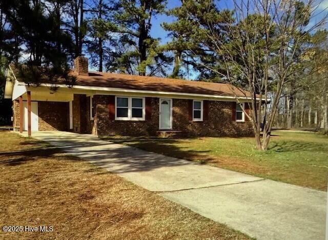 single story home with a chimney, brick siding, concrete driveway, a front yard, and a carport
