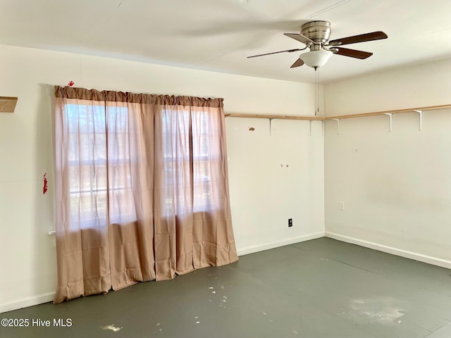 empty room with finished concrete flooring, baseboards, and a ceiling fan