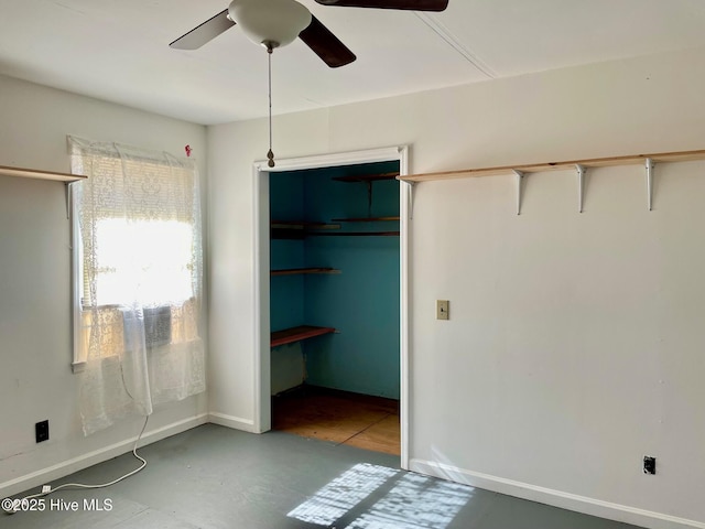 unfurnished bedroom featuring concrete flooring, baseboards, and ceiling fan