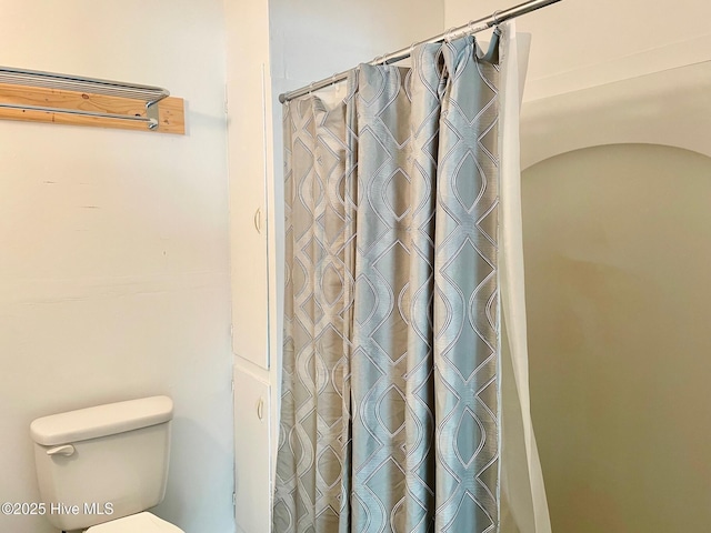 full bathroom with a shower with shower curtain and toilet