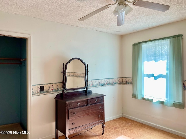 bedroom featuring baseboards, ceiling fan, wood finished floors, and a textured ceiling